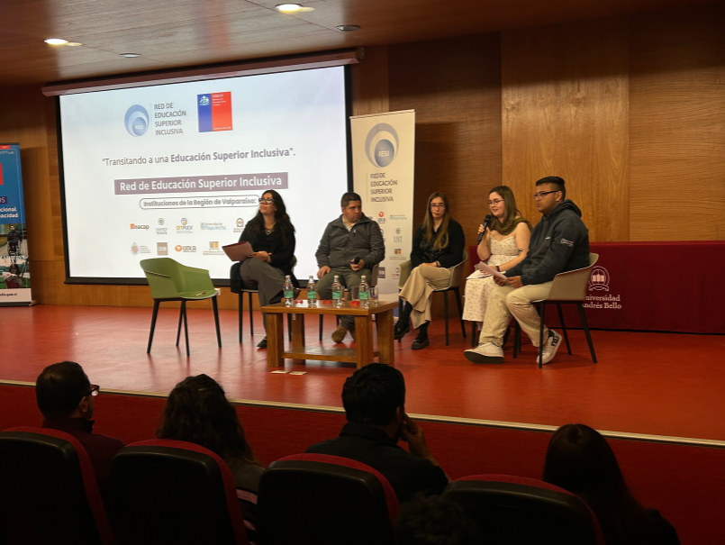 Cuatro estudiantes están sentados junto a profesional RESI, sobre escenario de Encuentro. Una estudiante sostiene el micrófono, exponiendo ante audiencia. 